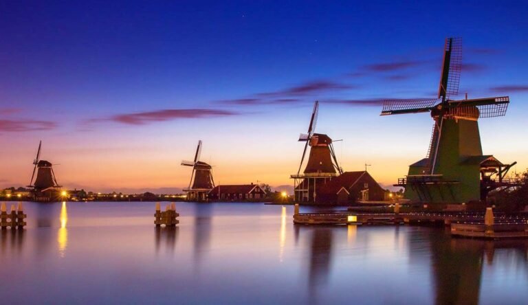 Dutch windmills along the water at dusk