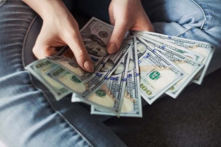 Hands holding a fan of US dollar banknotes