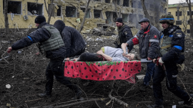 Rescue workers carrying a person on a stretcher through debris