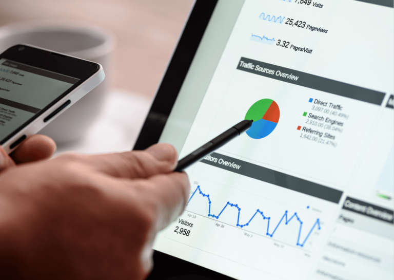 Hand with a pen pointing at charts on a tablet