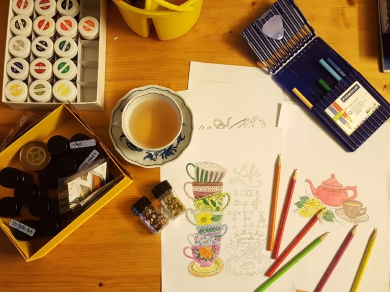 Desk with notebooks, coffee and art supplies seen from above