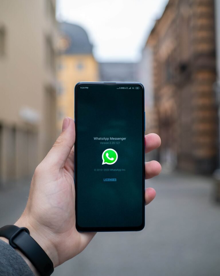 Hand holding a smartphone showing the WhatsApp logo