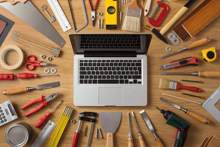 Laptop on a wooden table surrounded by tools
