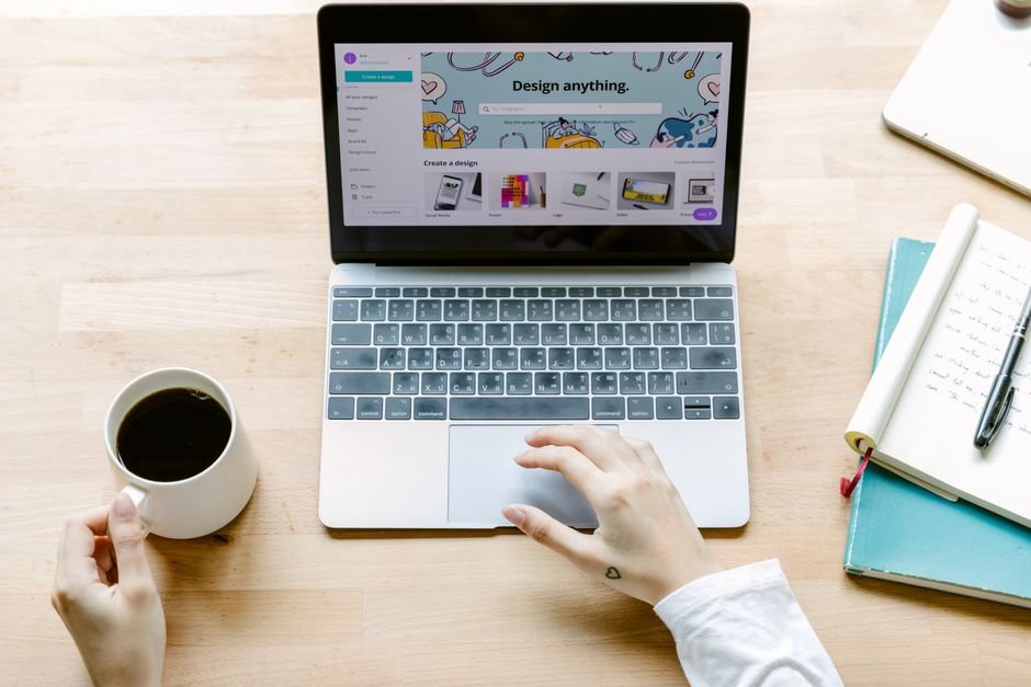 Professional working on customer emails at desk with laptop and notebook