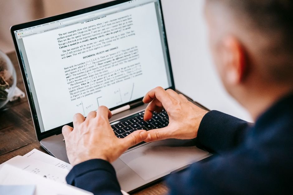 Person using laptop to translate official documents with smartphone nearby