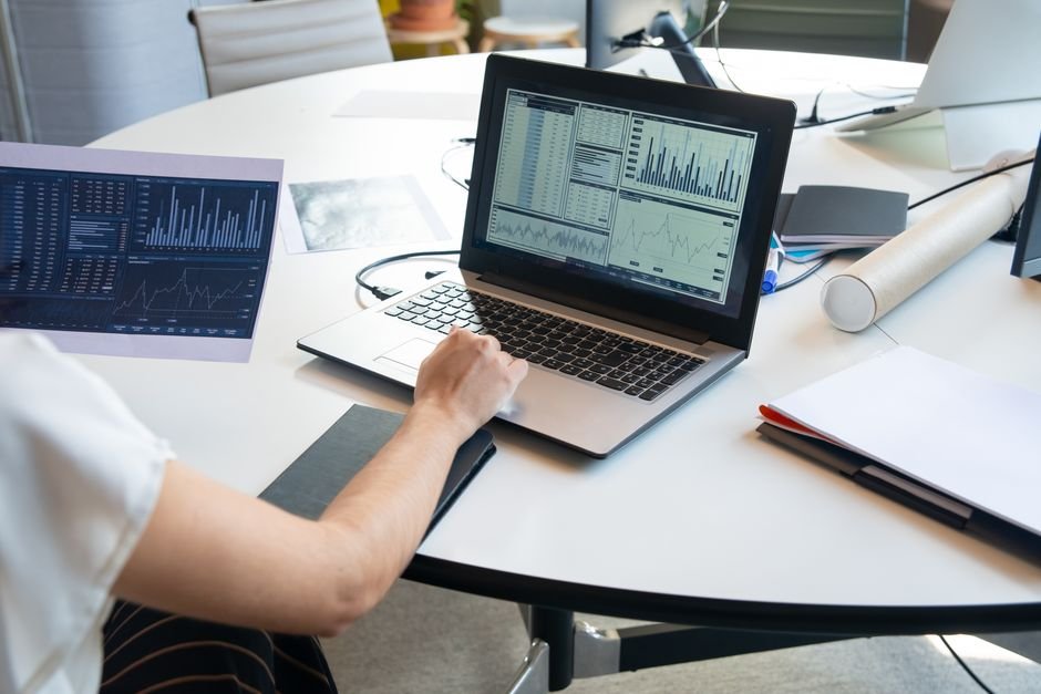Professional reviewing analytics data and charts on laptop for AI-powered reporting