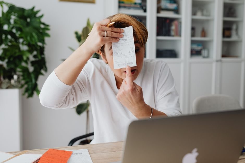 Freelancer organizing receipts and invoices on desk with laptop