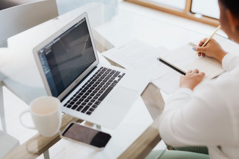 Freelancer writing job description on laptop at desk