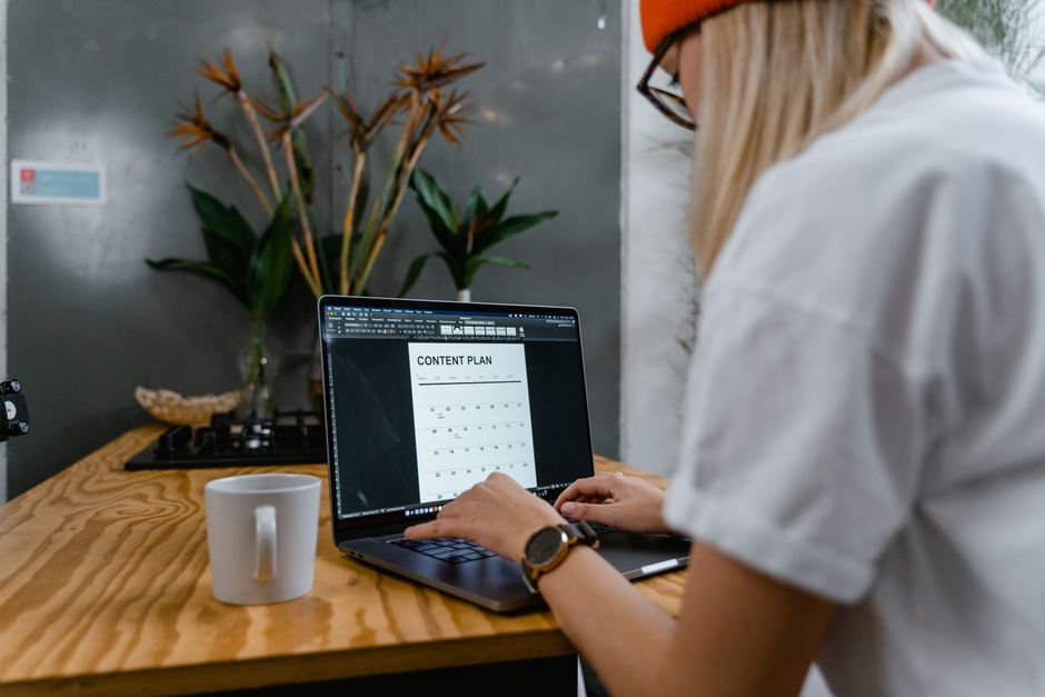 Freelancer planning marketing content on laptop with notes and coffee
