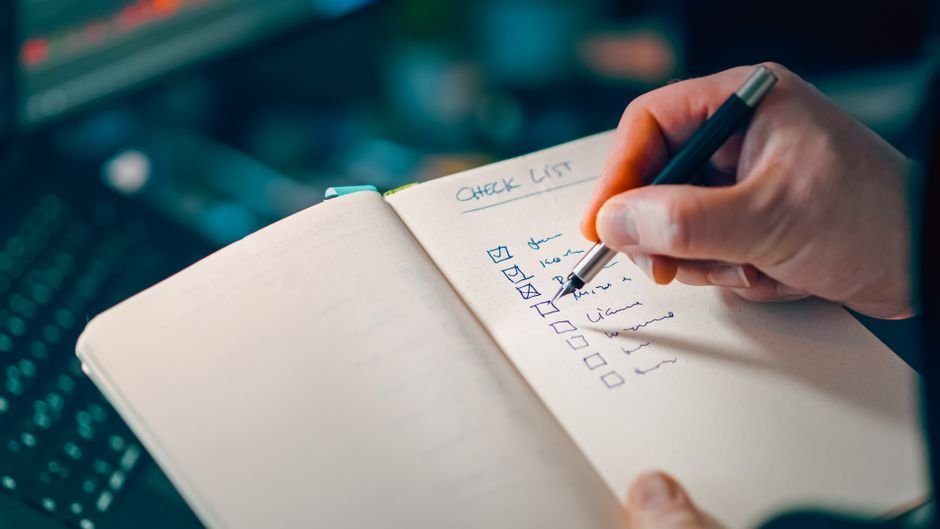 Checklist of acceptance criteria in notebook with pen