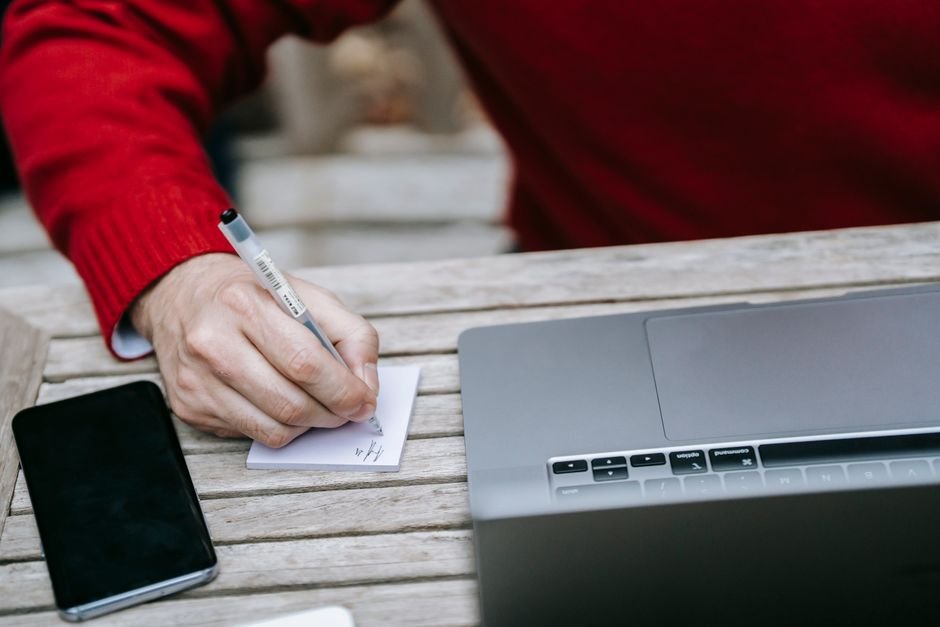 Business professional reviewing AI-generated content on laptop with notepad