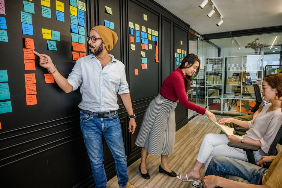 Team members collaborating during sprint planning session with sticky notes and laptop